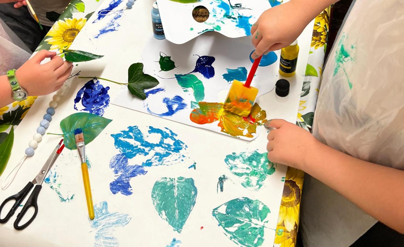 Children printing with leaves and paint during an Arts Award creative tutoring session