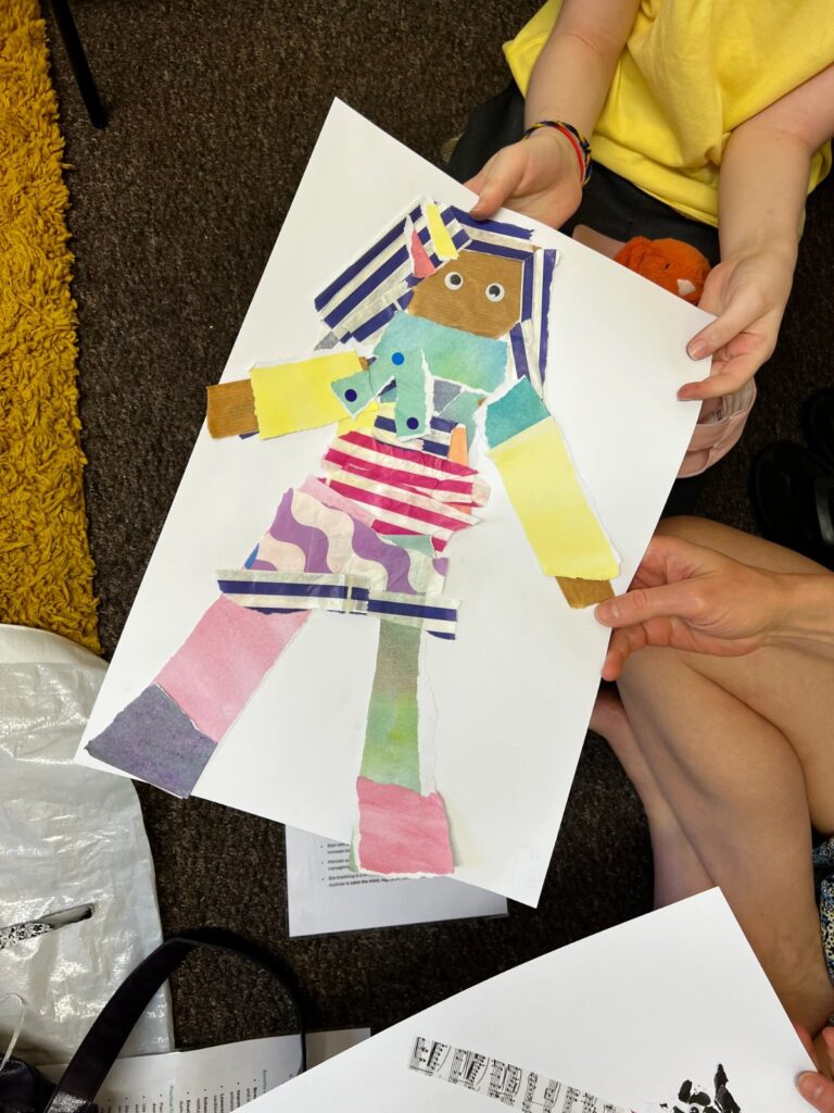 Child holding a collage figure artwork